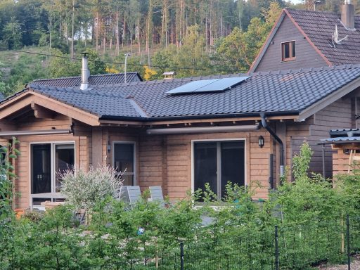Ein modernes Holzhaus mit einem Pfad und Solarzellen auf dem Dach.